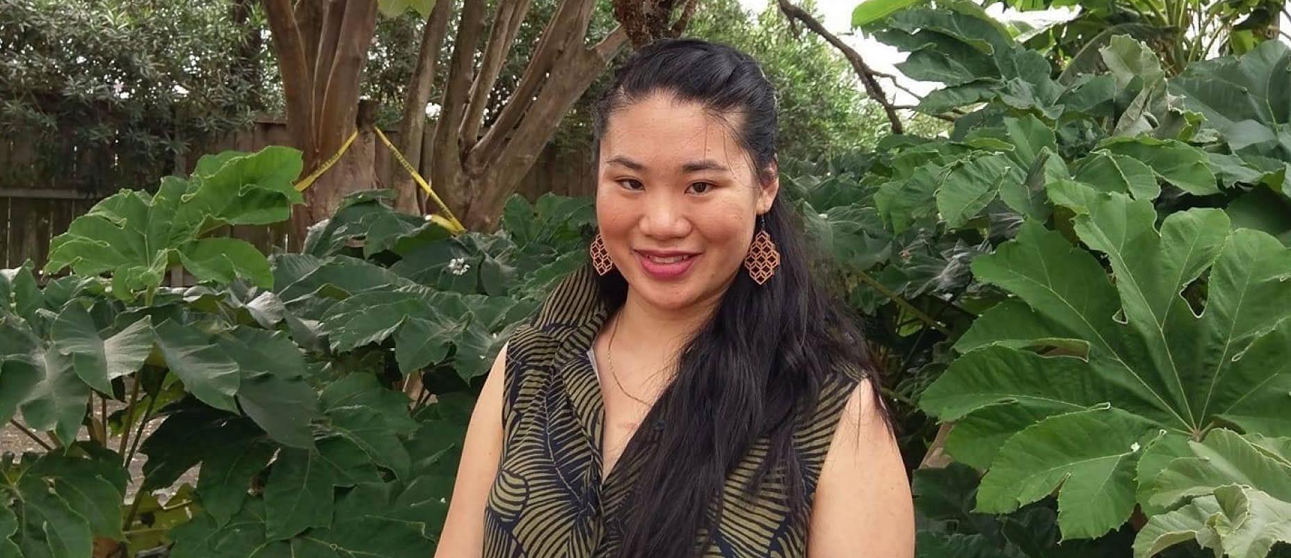 Larissa Fong standing in front of green leaves