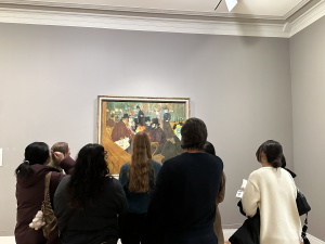 Students stand in a gallery looking at art.