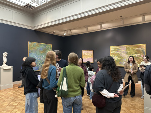 Students stand in a gallery looking at art.