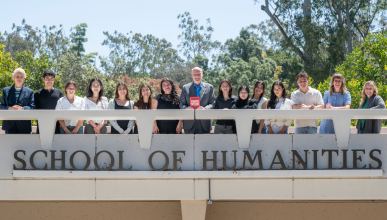 A group of students standing on the School of Humanities bridge with Chancellor Gillman.